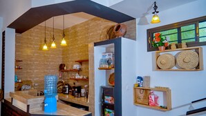 Una cocina con pared de ladrillo, estantes de madera, dispensador de agua y luces colgantes.