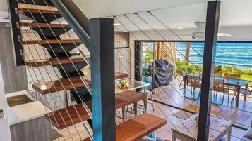 A modern interior with a staircase, wooden flooring, and a dining area with outdoor views.