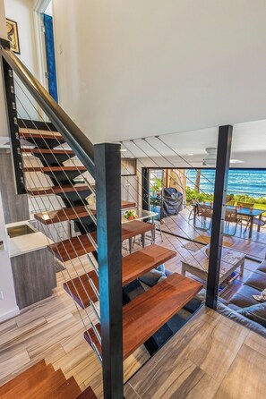 A modern interior with a staircase, wooden flooring, and a dining area with outdoor views.