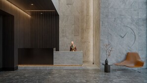 A modern reception area with a wooden panel wall, a stone reception desk, and a minimalist seating area with a single chair and a vase. - Chronos - Warszawa Wola by Downtown Apartments (Warsaw)