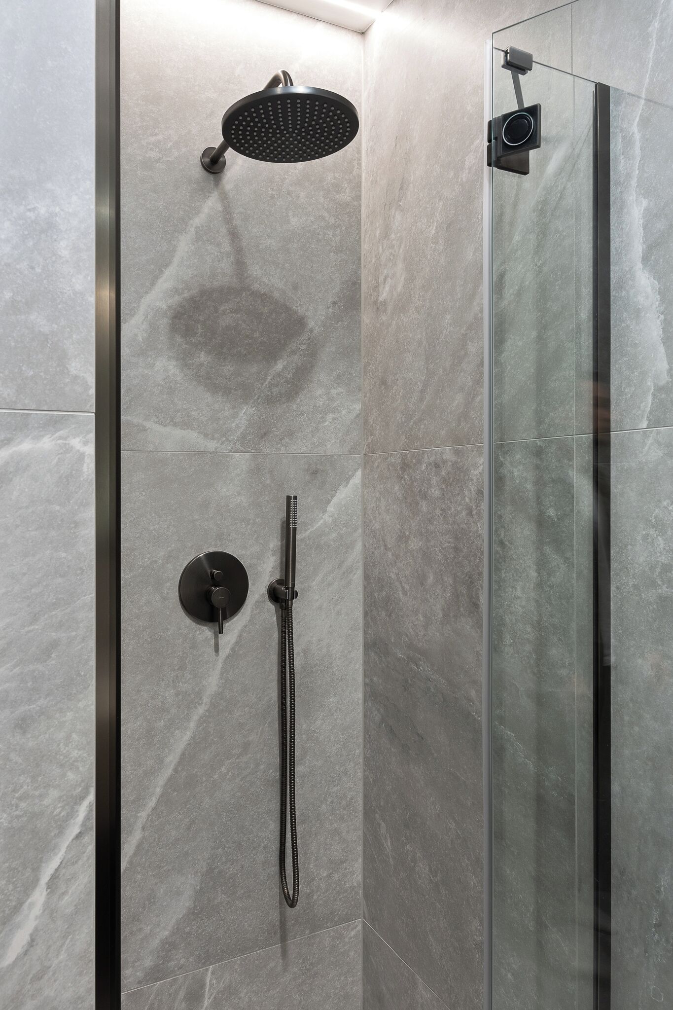 A modern shower with a handheld showerhead and a handheld shower nozzle.