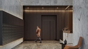 A modern interior with a man walking, a seating area, and a wall with lockers. - Chronos - Warszawa Wola by Downtown Apartments (Warsaw)