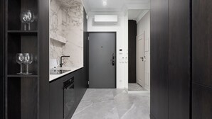 A modern kitchen with dark wood cabinets, a marble backsplash, and a built-in dishwasher. - Chronos - Warszawa Wola by Downtown Apartments (Warsaw)