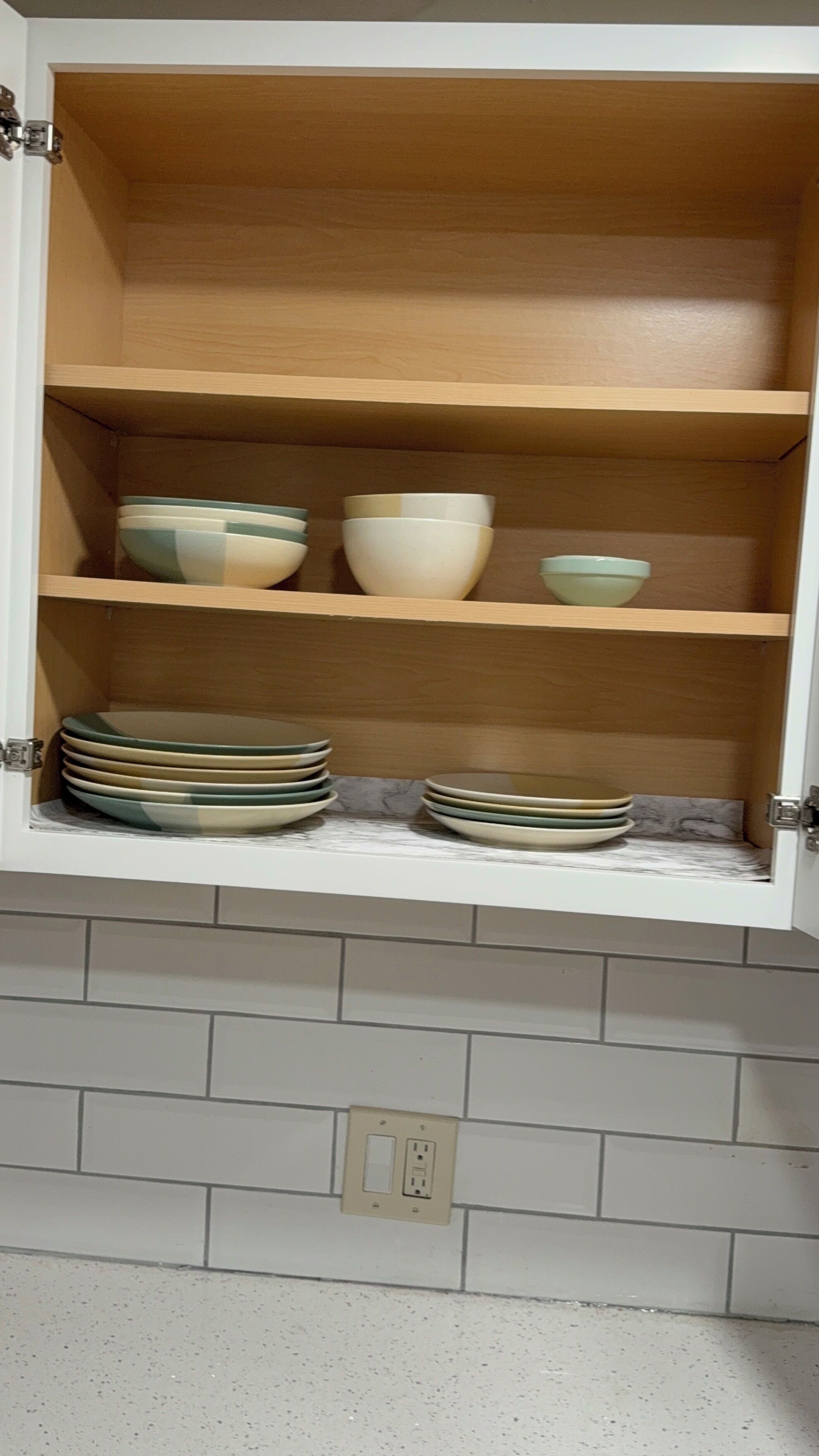 A kitchen cabinet with shelves holding bowls and plates.