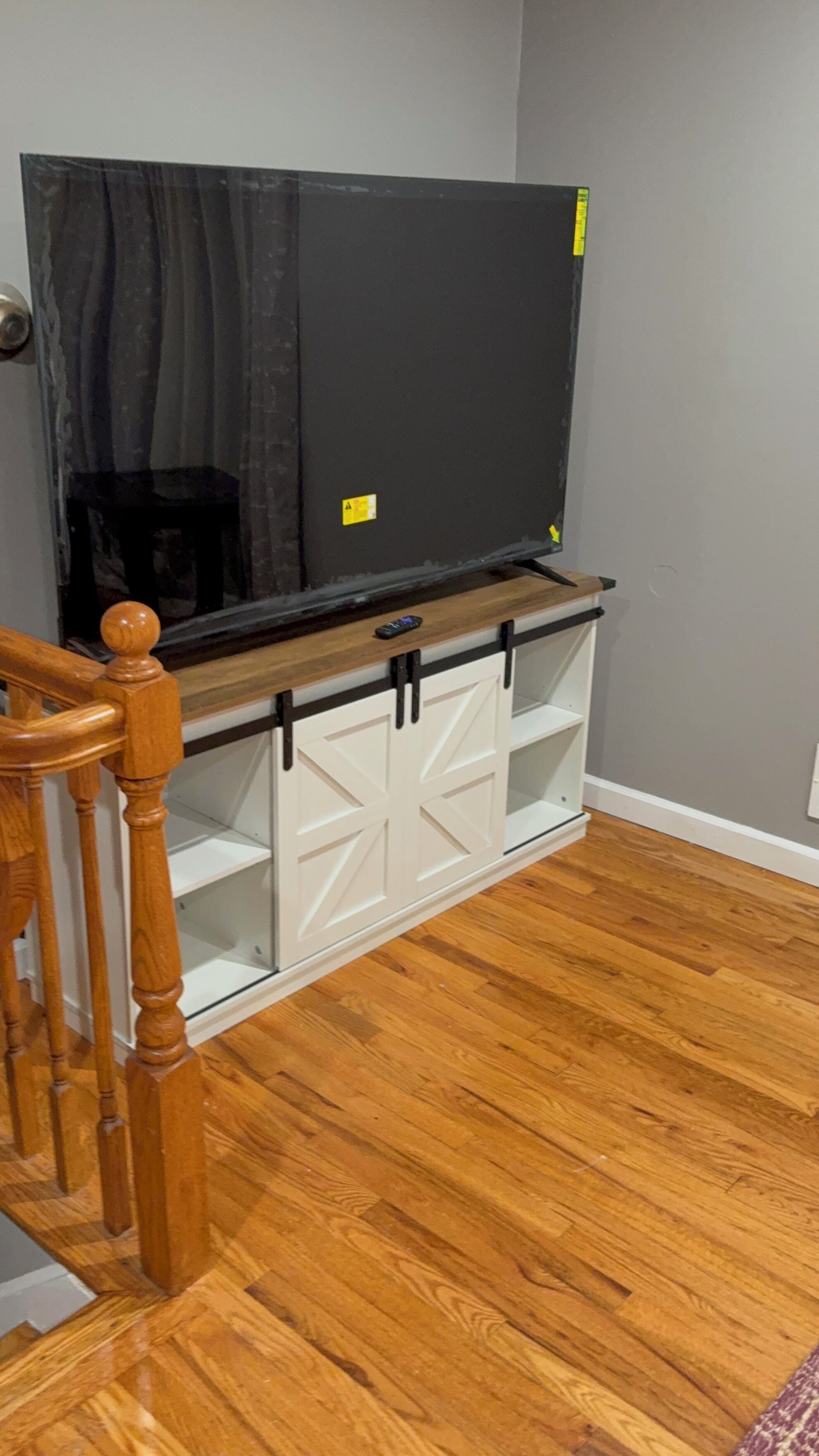 A wooden staircase with a TV on a white cabinet with sliding doors.