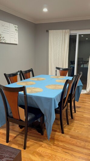 A dining area with a blue tablecloth, wooden chairs, and a wall with a religious poster. - Fabulous 2-bedroom apartment non smoking  with huge yard and work station.deck, (North Brunswick Township)