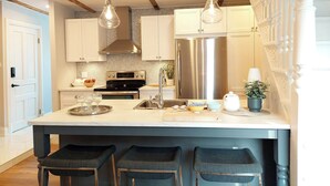 A kitchen with a central island, stainless steel appliances, pendant lighting, and a white tiled backsplash. - 25SV2-VE Ouimetoscope (Québec)