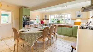 Una cocina amplia con comedor, armarios verdes y un ventanal que proporciona luz natural.
