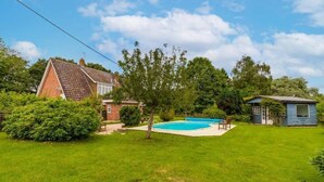Un patio trasero con piscina, un cobertizo pequeño y una casa con techo inclinado.