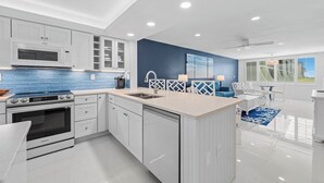A modern kitchen with white cabinetry, a blue backsplash, and a large island.