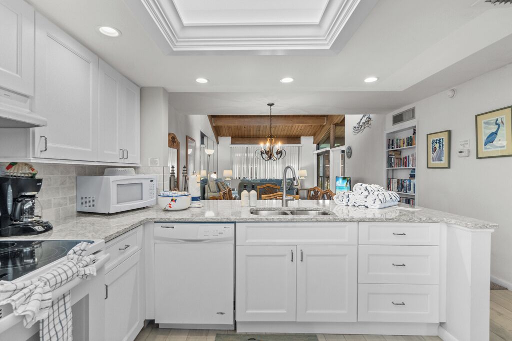 A modern kitchen with white cabinetry, a built-in microwave, and a large island with a sink.