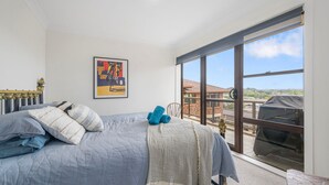 Une chambre avec un grand lit, une fenêtre donnant sur un beau paysage et un tableau encadré accroché au mur.