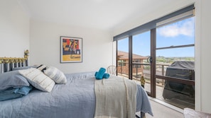 Een slaapkamer met een groot bed, een raam met uitzicht en een lijst met een afbeelding aan de muur.