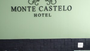 A reception desk with a black tiled backsplash and a sign above it that reads "Monte Castelo Hotel". - HOTEL MONTE CASTELO LTDA. (Rio de Janeiro)