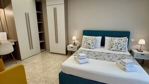 A modern bedroom with a large bed, a wardrobe, a desk, and a chair. - Casa Anatrella Comfort House (Naples)