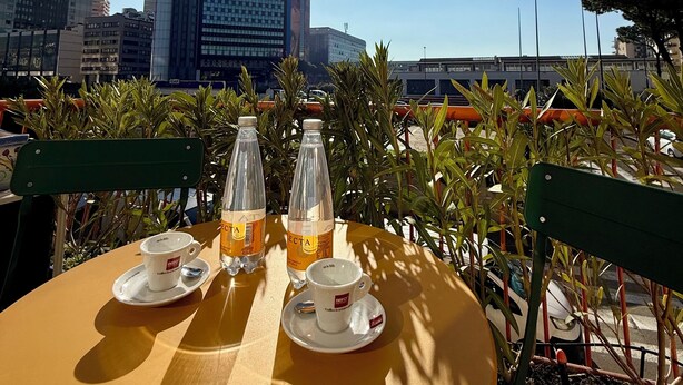 A table with two cups and two bottles of water, set outdoors with a cityscape in the background. - Casa Anatrella Comfort House (Naples)