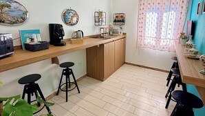 A compact kitchen with a wooden countertop, a coffee machine, and a sink. There are two stools and a potted plant. - Casa Anatrella Comfort House (Naples)