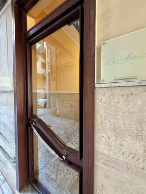 A hotel entrance with a dark wooden door, a metal handle, and a sign with the hotel's name and contact information. - Casa Anatrella Comfort House (Naples)