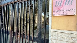 A hotel entrance with a metal gate, a sign for 'Casa Anatrella' indicating a hotel and spa, and another sign for 'mfm' which is likely a beauty salon. - Casa Anatrella Comfort House (Naples)