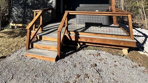 Eine kleine Holzhütte mit einer Holzterrasse und einem überdachten Veranda-Bereich.
