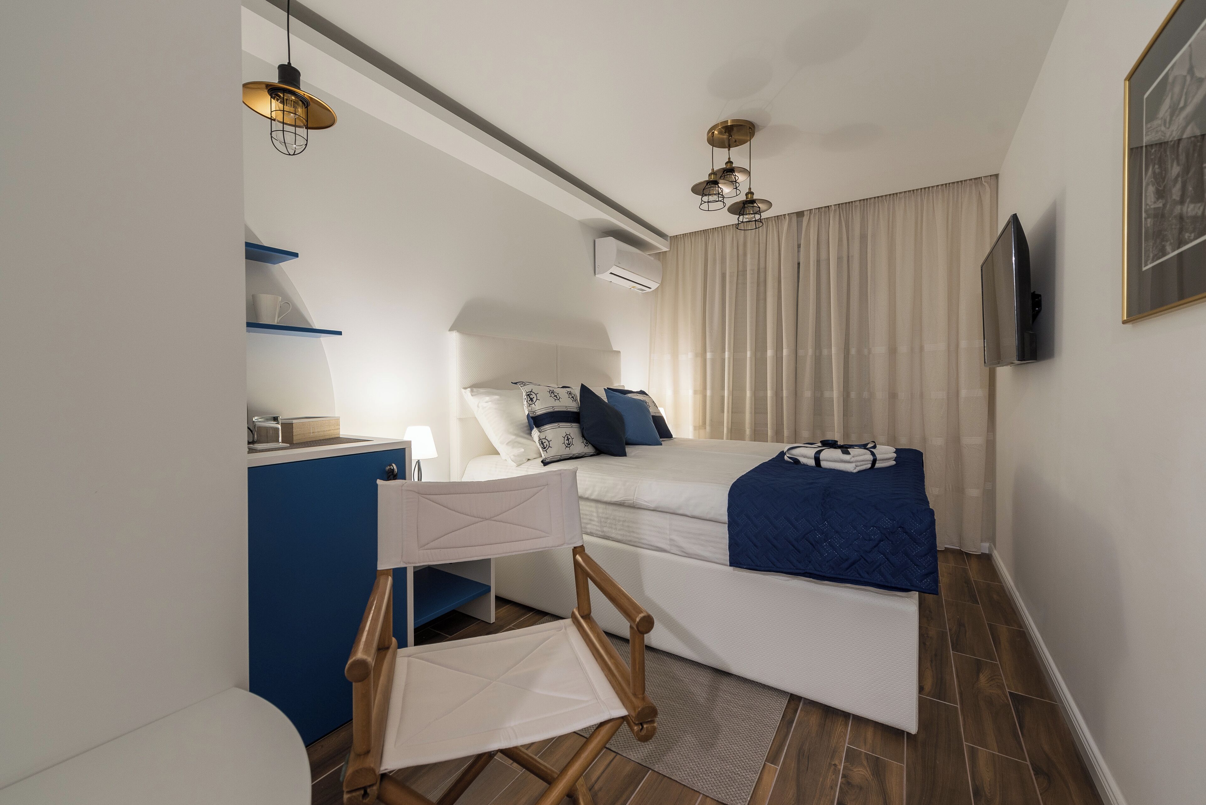 Ein modernes Hotelzimmer mit Bett, Schreibtisch, Stuhl und Fernseher.