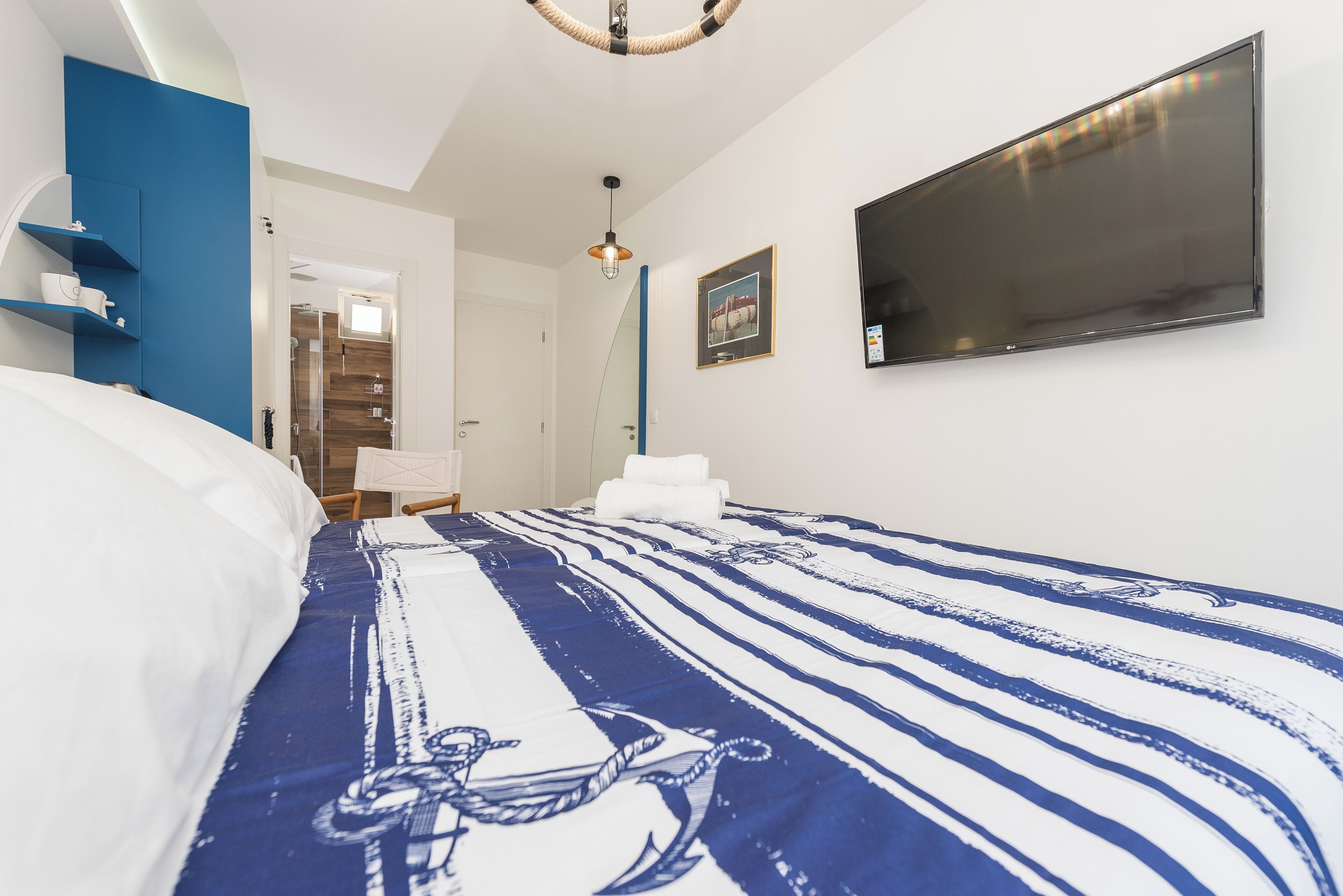 A bedroom with a bed, a TV, a shower, and a door leading to a bathroom.