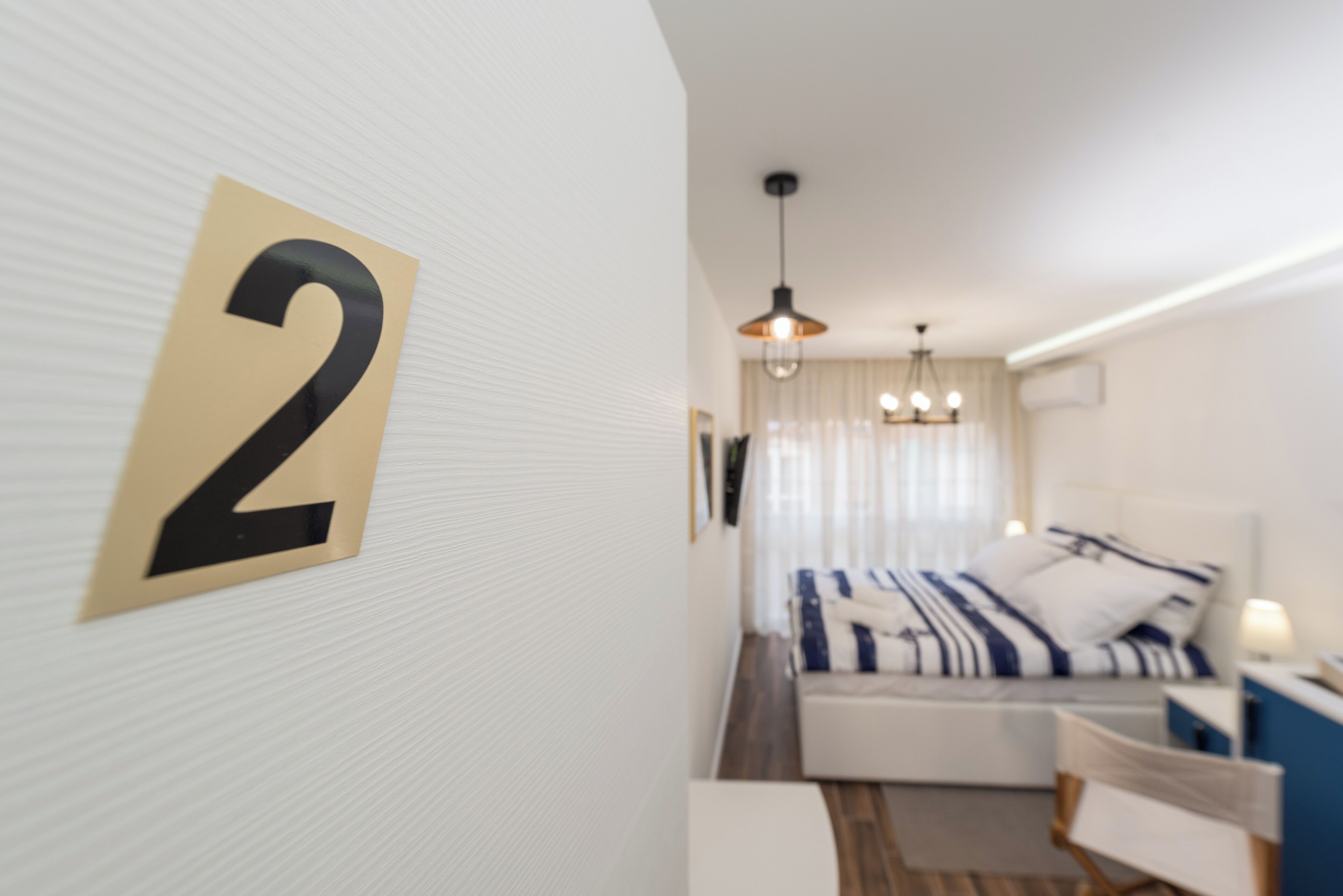 A hotel room with a bed, a desk, and a large number '2' on the wall.