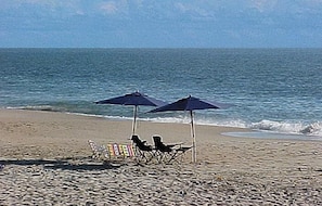 Une plage avec deux parasols et des chaises de plage.