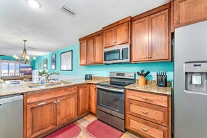 A kitchen with wooden cabinets, a stainless steel microwave, oven, and refrigerator.