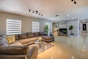 A modern living room with a sectional sofa, a coffee table, and a fireplace. - Luxury Resort • Gym, Cold Plunge, Jacuzzi & Sauna (Miami)