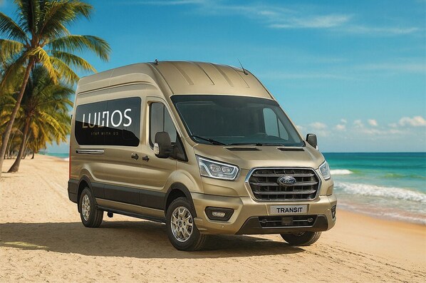 En beige skåpbil stod parkerad på en sandstrand med palmer i bakgrunden.