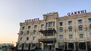 A hotel with a classical facade, featuring the names "REIKARTZ" and "QARSHI" on the upper levels. - Reikartz Qarshi (Qarshi)