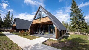A modern house with a triangular roof, large windows, and a wooden deck. - Mountain homes Durmitor 2 (Uskoci)
