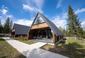 Una casa moderna con techo triangular, ventanas amplias y una terraza de madera.