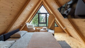 A cozy attic bedroom with a large window, a bed, a chair, and a TV. - Mountain homes Durmitor 2 (Uskoci)