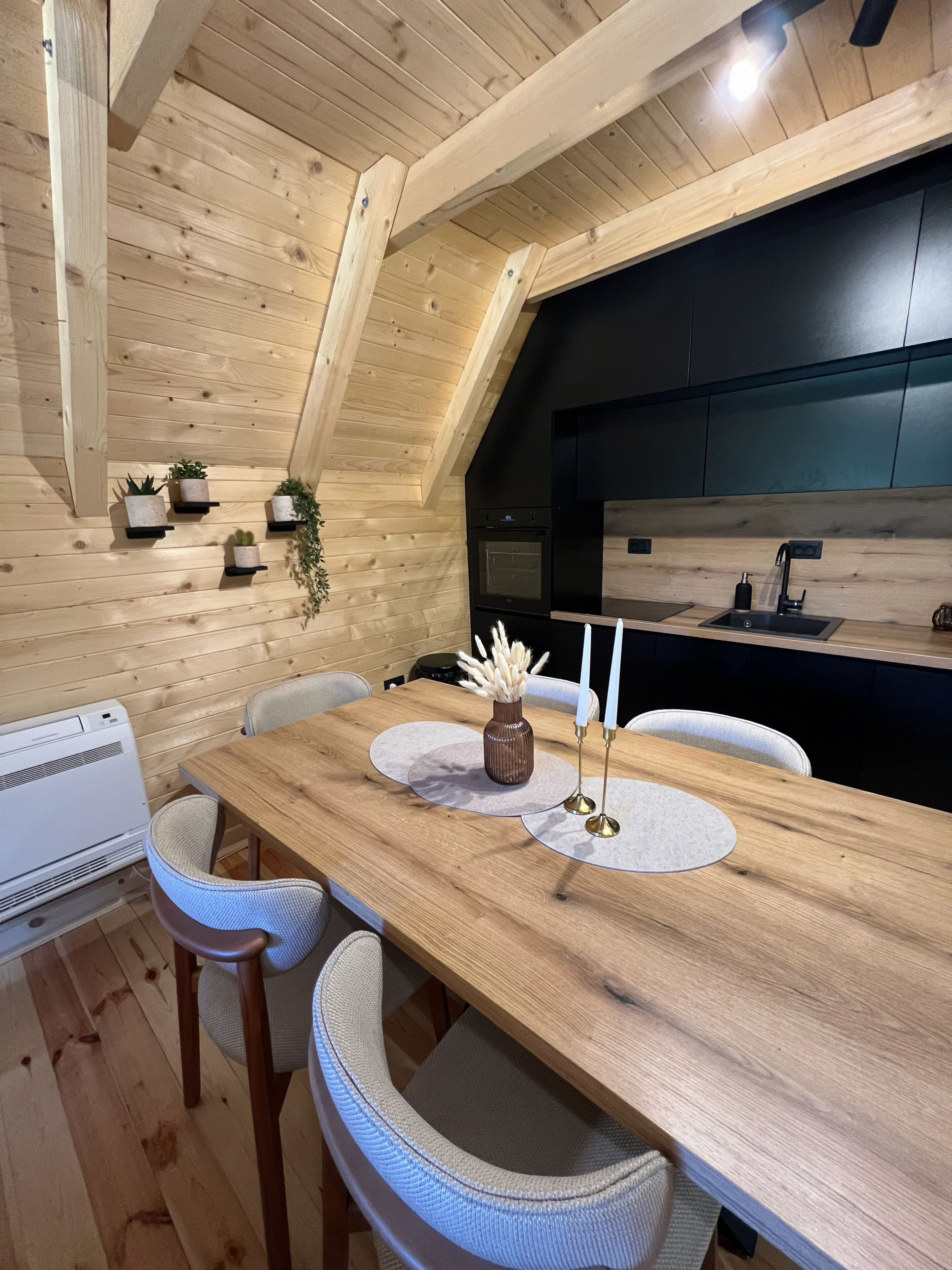 Un tavolo da pranzo in legno con sedie, un vaso e candele.
