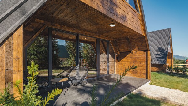 A modern wooden house with a covered patio, large windows, and outdoor seating. - Mountain homes Durmitor 2 (Uskoci)