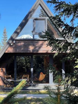 A modern house with a triangular roof, large windows, and a patio with outdoor furniture. - Mountain homes Durmitor 2 (Uskoci)