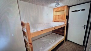 A small, compact room with a bunk bed, a wardrobe, and a ceiling fan. - Studio le lioran "les sagnes (Laveissière)