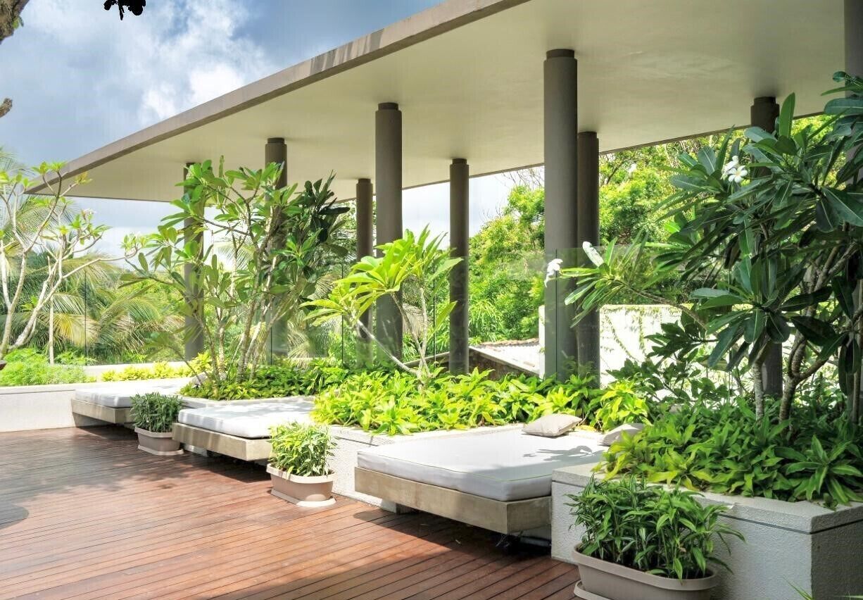 A covered outdoor area with a wooden deck, planters with greenery, and a modern architectural design.