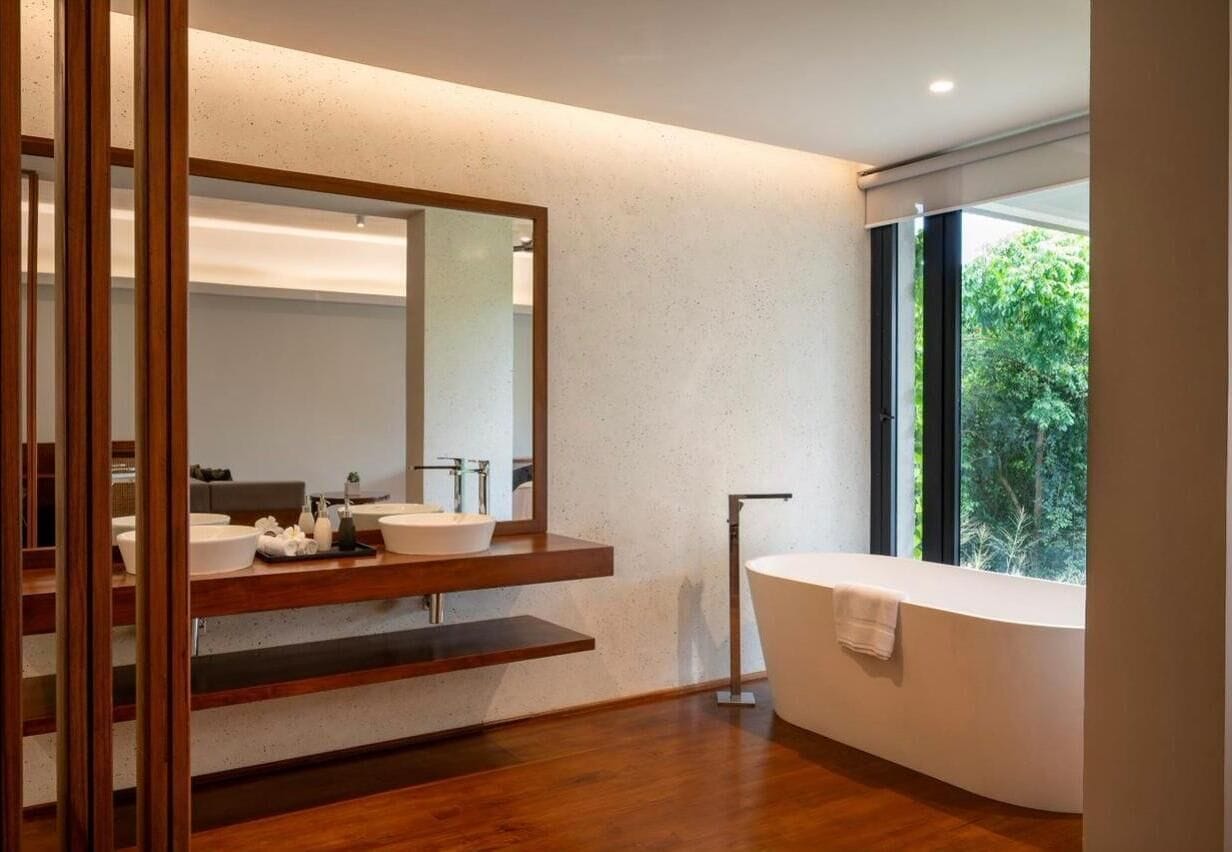 A modern bathroom with a freestanding bathtub, a large mirror, and a wooden vanity.