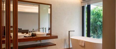 A modern bathroom with a freestanding bathtub, a large mirror, and a wooden vanity.