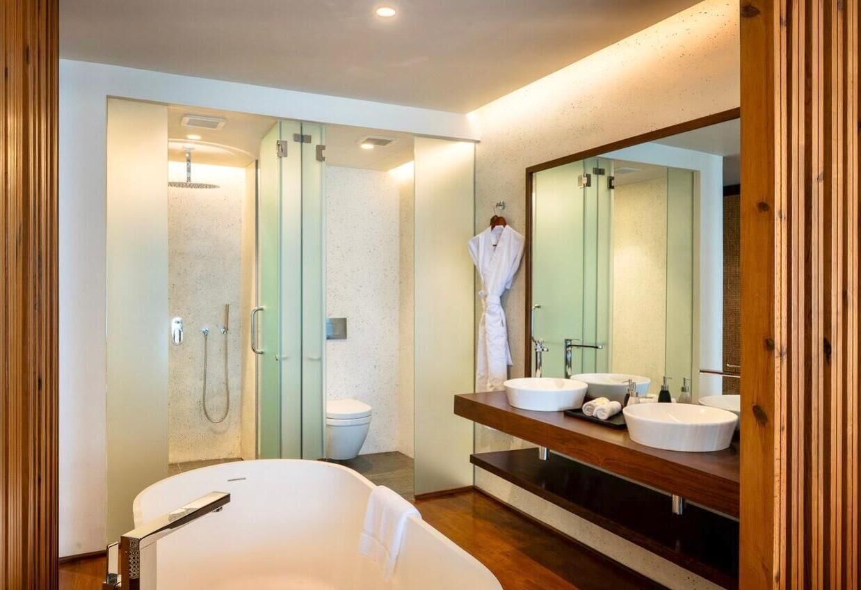 A modern bathroom with a freestanding bathtub, a large mirror, and a vanity with two sinks.