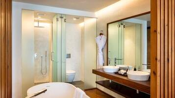 A modern bathroom with a freestanding bathtub, a large mirror, and a vanity with two sinks.