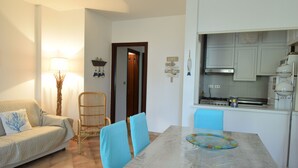 Un comedor con una mesa, sillas, una lámpara y una cocina al fondo.