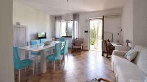 Un amplio espacio habitable con una mesa de comedor, sillas, un sofá y una televisión.