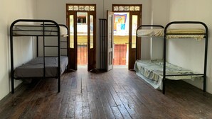 Una stanza con due letti a castello, pavimento in legno e una porta che dà su una zona esterna.