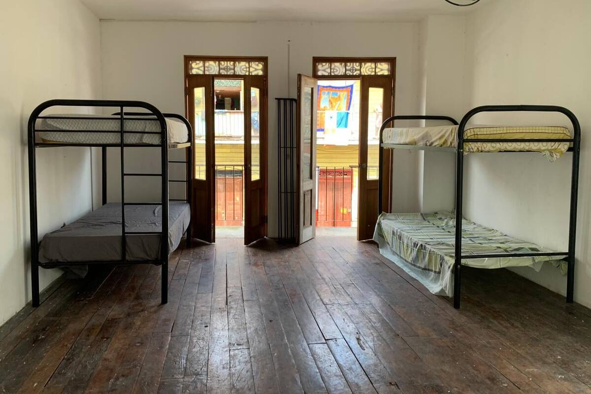 A room with two bunk beds, wooden flooring, and a door leading to an outdoor area.