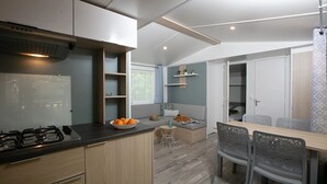 Een kleine keuken met een gasfornuis, een schaal mandarijnen en een eethoek met een tafel en stoelen.