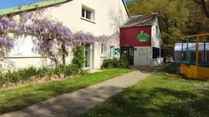 A building with a green roof, a red door, and a sign with a green logo. - ZEcamping 3* piscine chauffée dog friendly sauna locatif 28m2 4 pers (Huelgoat)